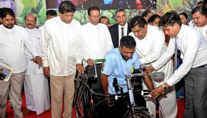 H.E. the President presents a tricycle to a Sales Assistant of DLB